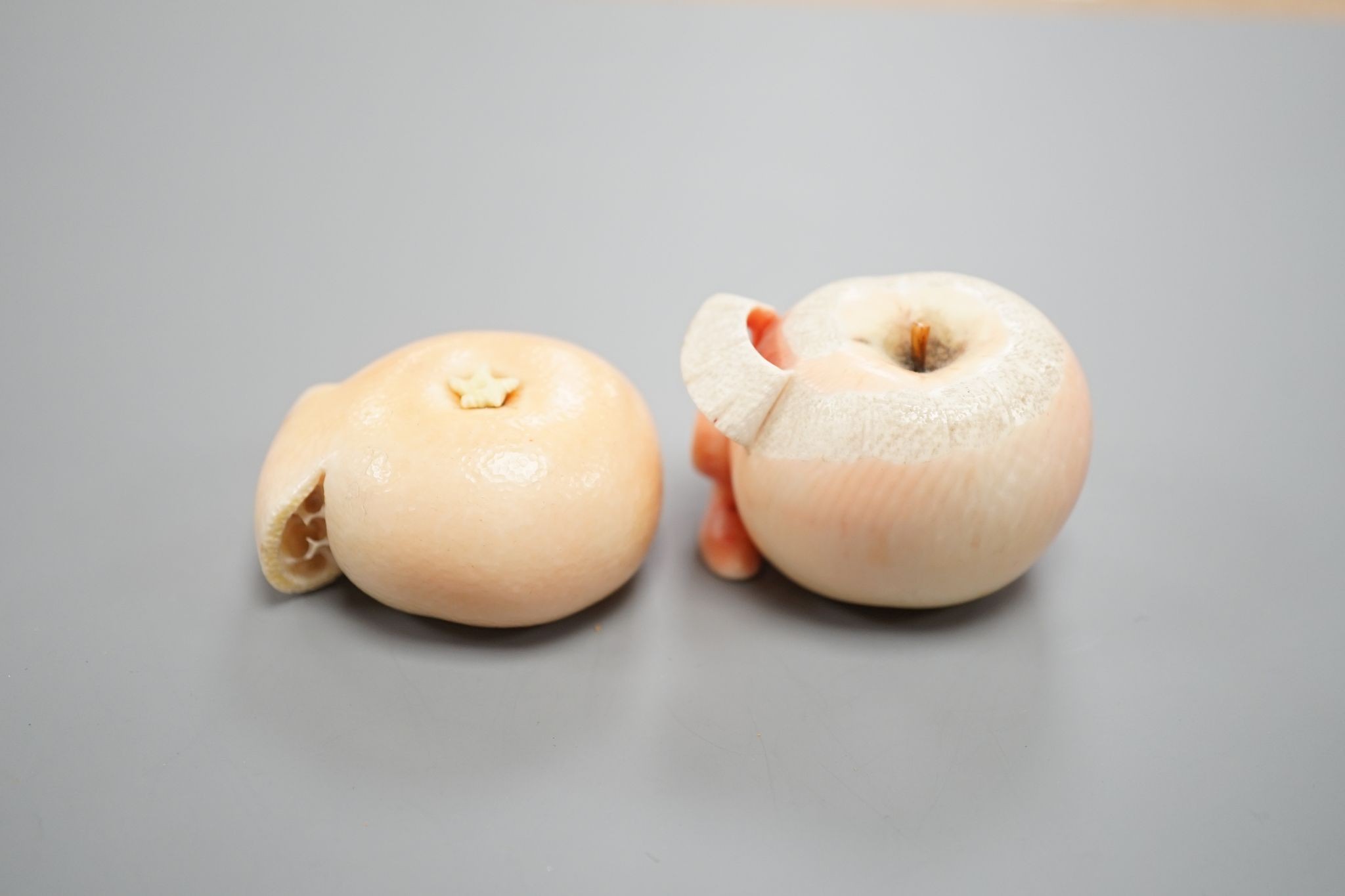 Two Japanese ivory models of a peeled apple and a satsuma, Meiji period, 3.5 cms high.